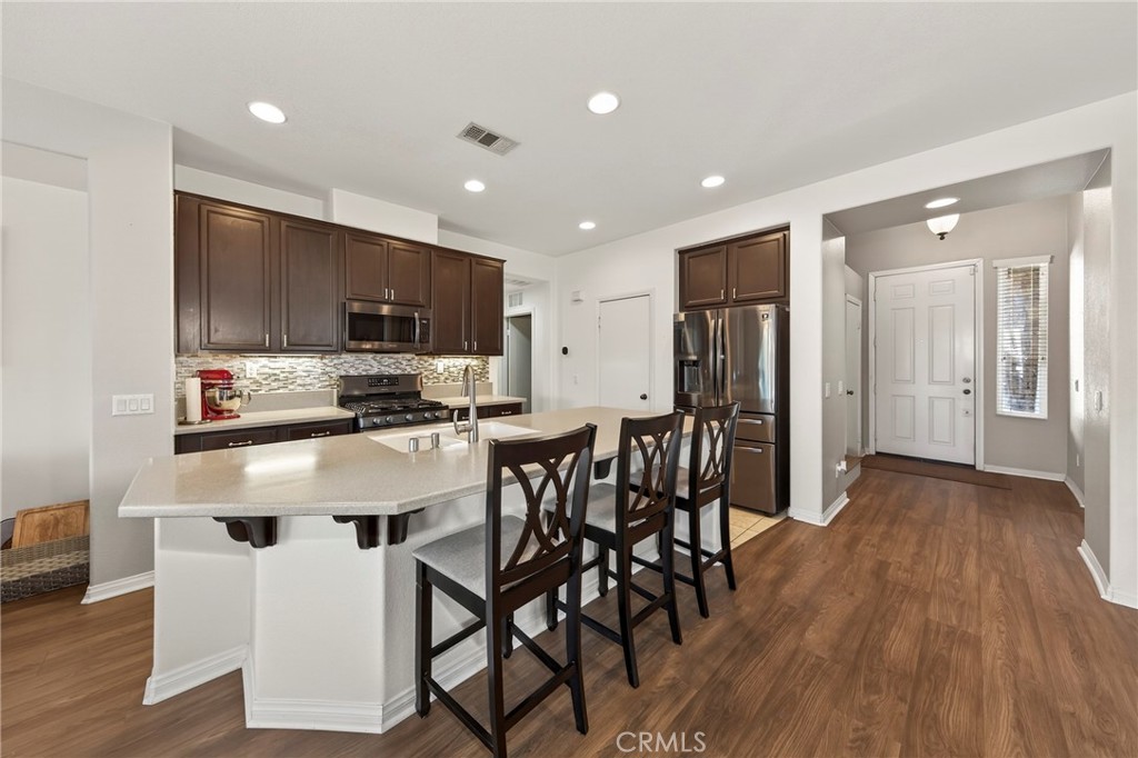 1433 Fall Brook Road Beaumont, CA 92223 - Photo 7 of 33 a kitchen with stainless steel appliances a dining table chairs refrigerator and microwave