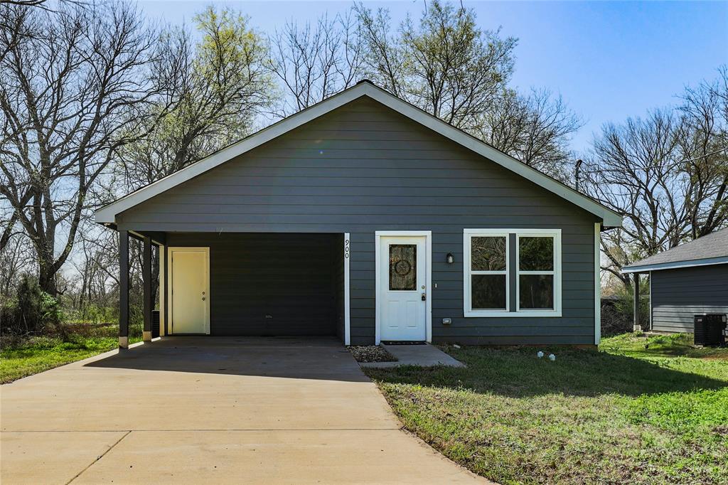 View of front of property with central air condition unit, concrete driveway, and a front yard