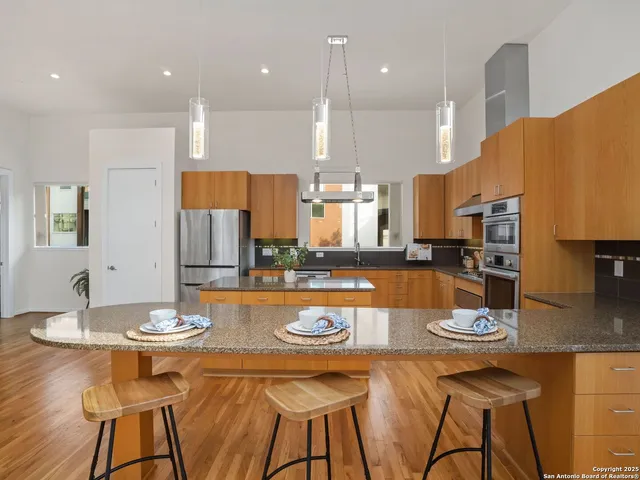 a large kitchen with stainless steel appliances granite countertop a refrigerator a stove and a sink