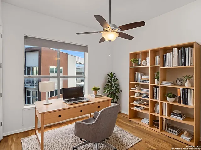 a view of empty room with wooden floor and fan