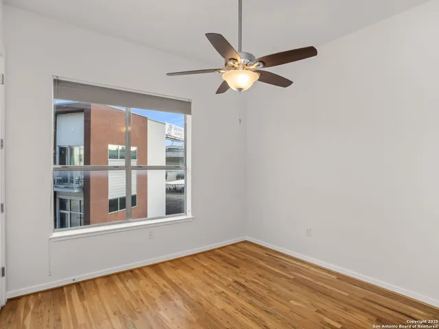 an empty room with wooden floor fan and windows