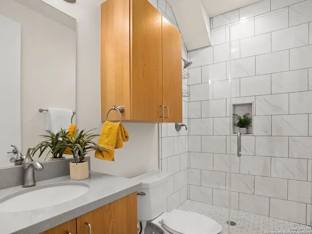 a bathroom with a granite countertop sink a toilet and mirror
