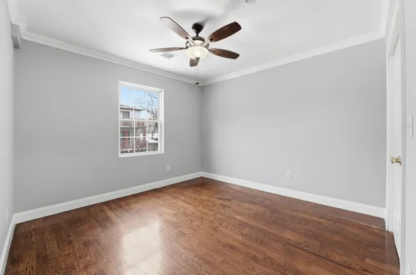an empty room with wooden floor and ceiling fan