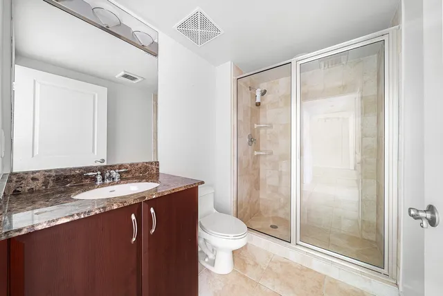 a bathroom with a granite countertop sink toilet and shower