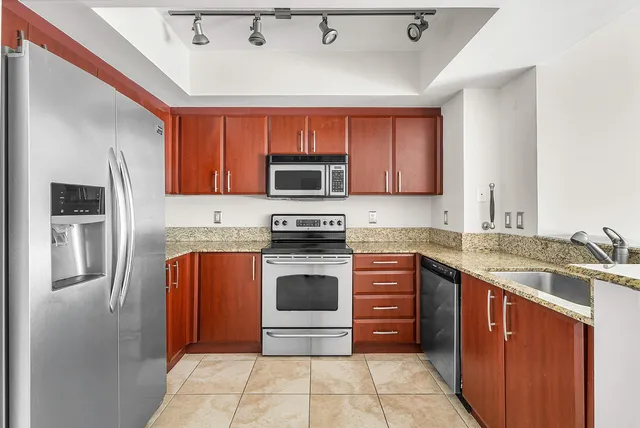 a kitchen with stainless steel appliances granite countertop a stove top oven a sink and dishwasher