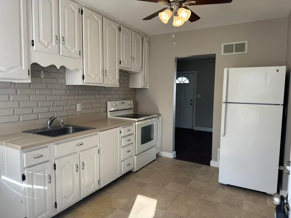 a kitchen with white cabinets and white appliances