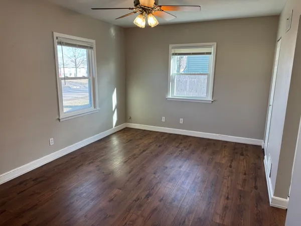 a view of an empty room with wooden floor and a window