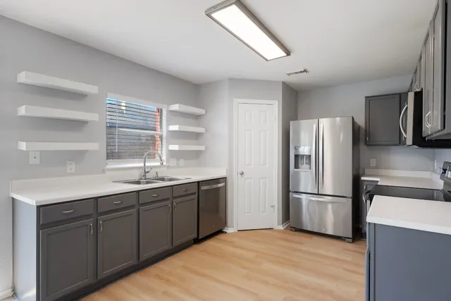 a kitchen with stainless steel appliances a sink cabinets and wooden floor