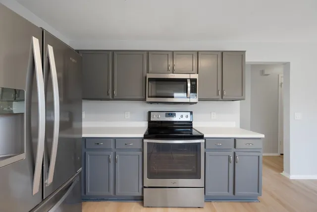 a kitchen with cabinets stainless steel appliances and wooden floor
