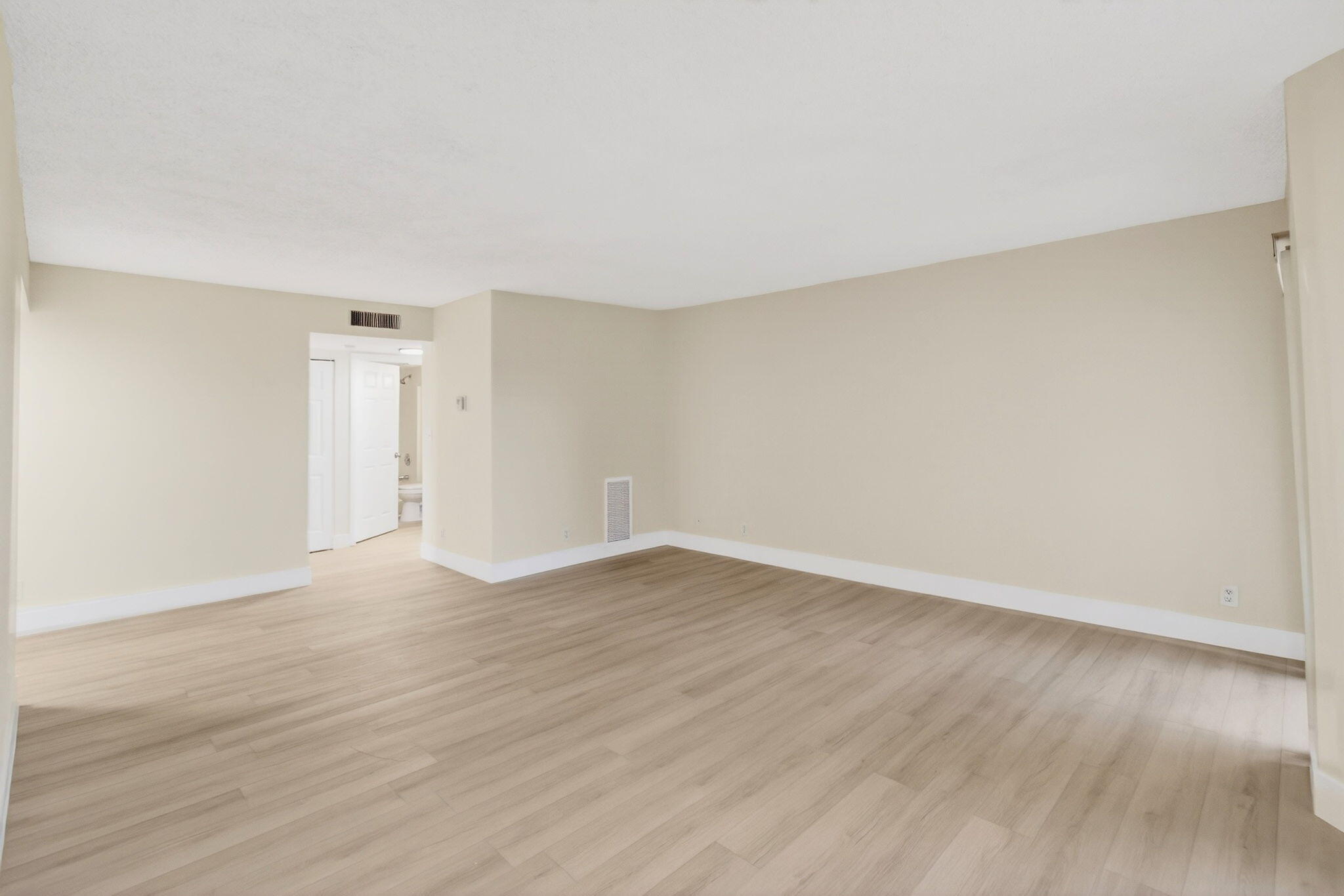 5900 Camino Del Sol, Unit 304 Boca Raton, FL 33433 - Photo 18 of 82 a view of an empty room with wooden floor and a window