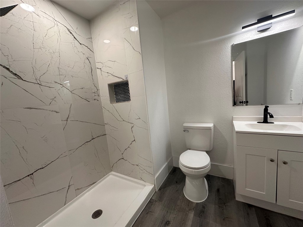720 Neches Street Lockhart, TX 78644 - Photo 10 of 12 Second full bathroom with vanity, a marble-style walk-in shower, and dark wood-style floors