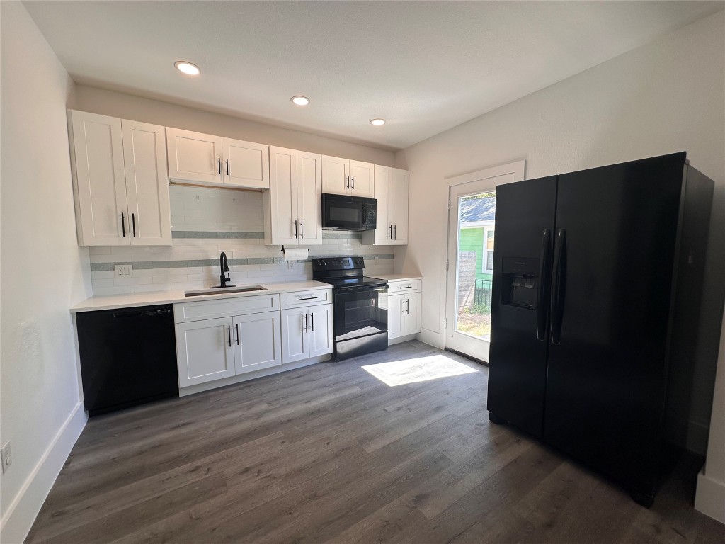 720 Neches Street Lockhart, TX 78644 - Photo 3 of 12 Kitchen with black appliances, white cabinetry, tasteful backsplash, dark wood-type flooring, and recessed lighting