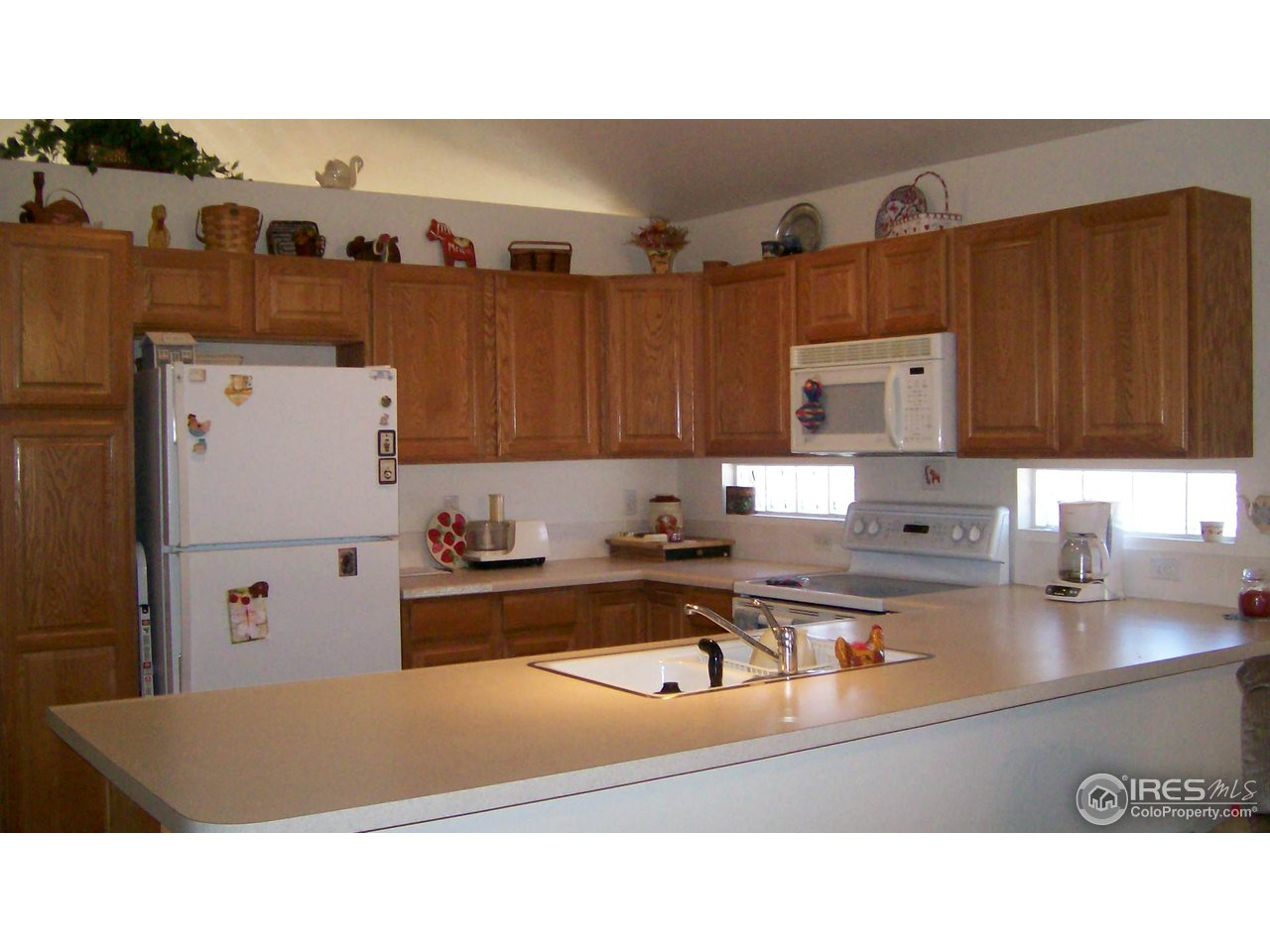 3597 West 21st Street Road Greeley, CO 80634 - Photo 4 of 12 a kitchen with kitchen island a stove a refrigerator a sink and dishwasher with wooden cabinets