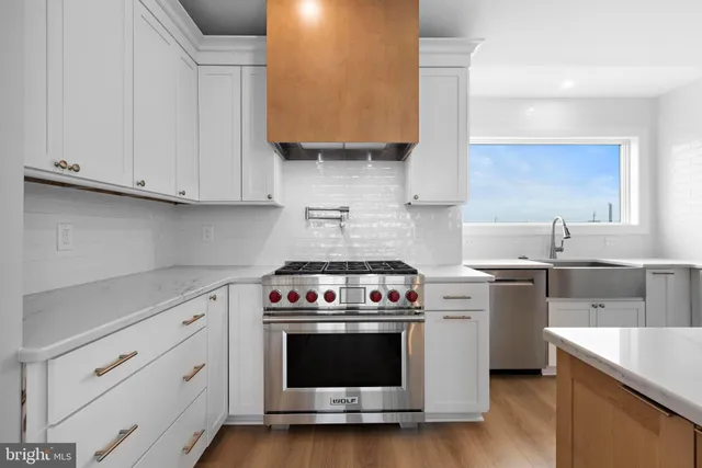a large white kitchen with a large window a sink and stainless steel appliances