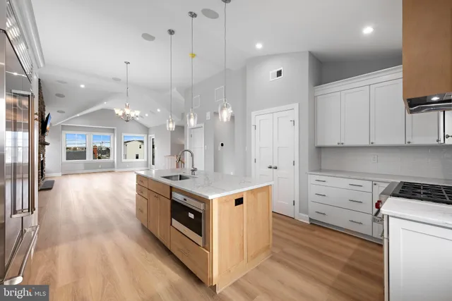 a view of kitchen with stainless steel appliances granite countertop a stove top oven a sink dishwasher a refrigerator and white cabinets with wooden floor
