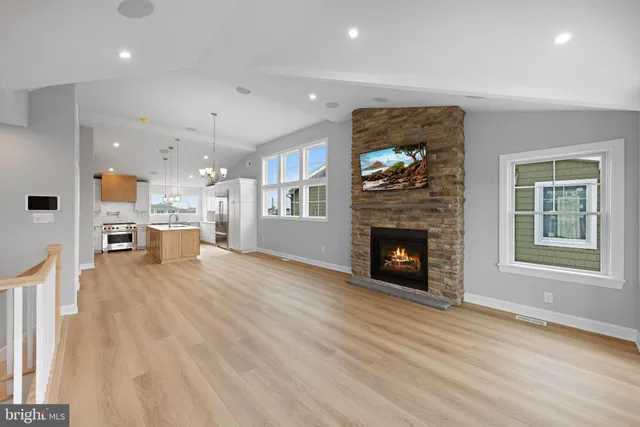 a view of an empty room with wooden floor fireplace and a window