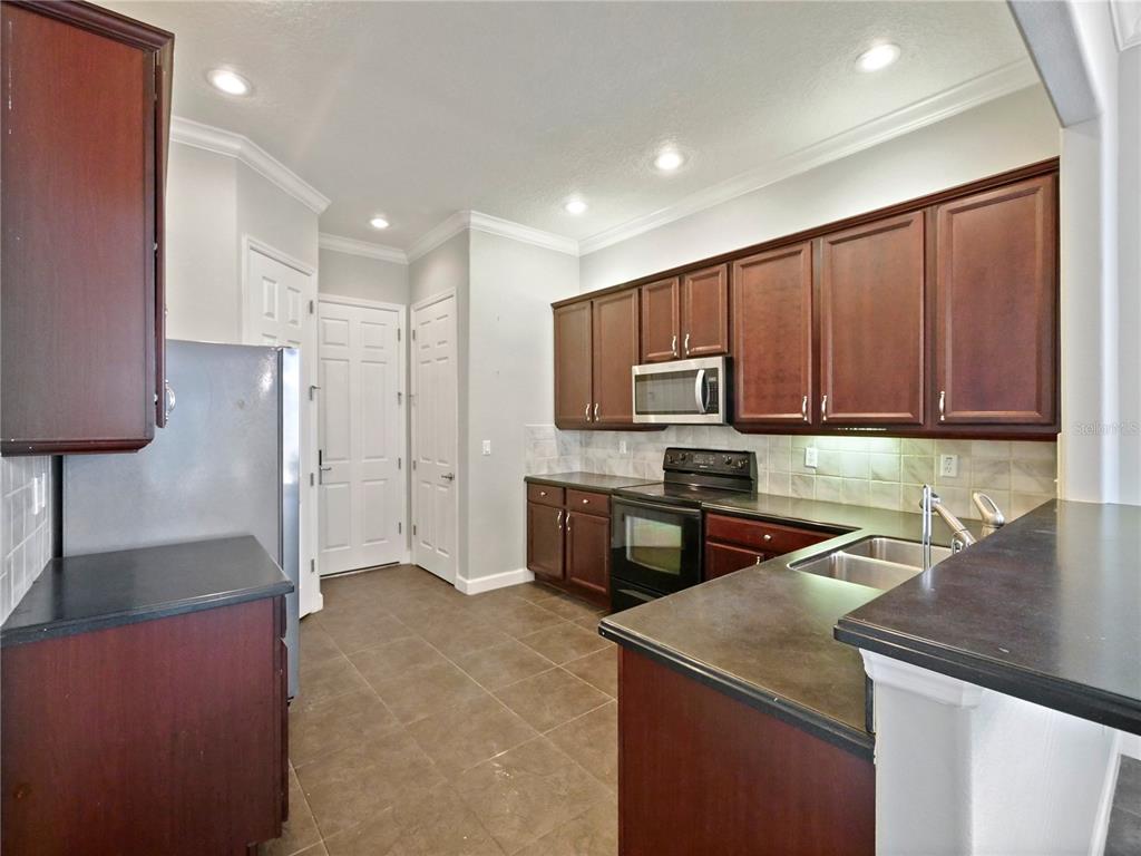 7710 Linkside Loop Reunion, FL 34747 - Photo 24 of 33 a kitchen with stainless steel appliances granite countertop a sink refrigerator and microwave