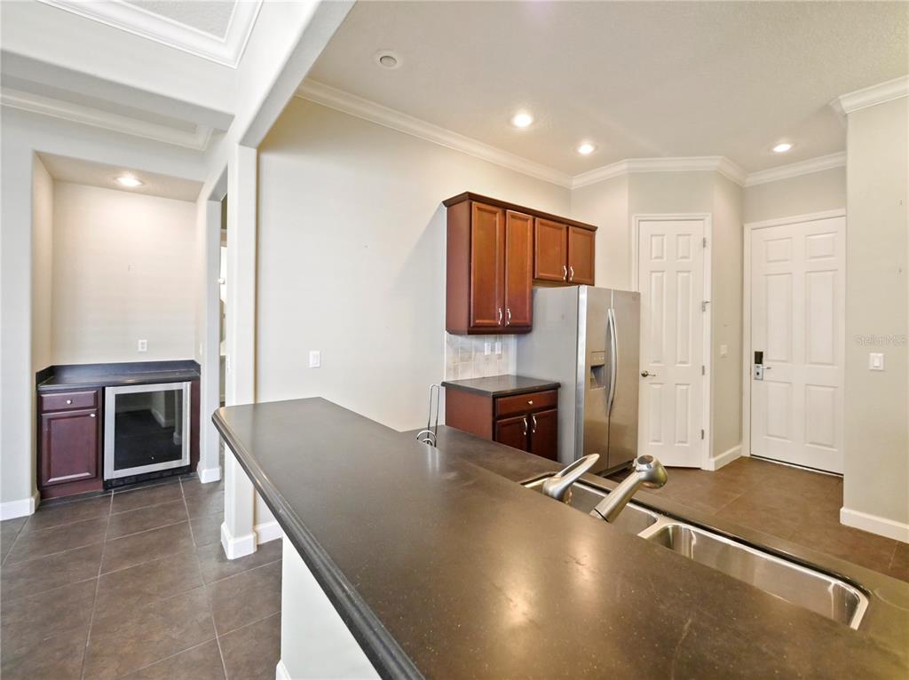 7710 Linkside Loop Reunion, FL 34747 - Photo 25 of 33 a kitchen with stainless steel appliances granite countertop a refrigerator a stove and a sink with wooden floor