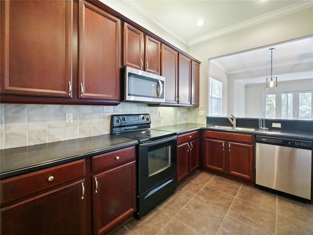 7710 Linkside Loop Reunion, FL 34747 - Photo 26 of 33 a kitchen with stainless steel appliances granite countertop a sink and cabinets
