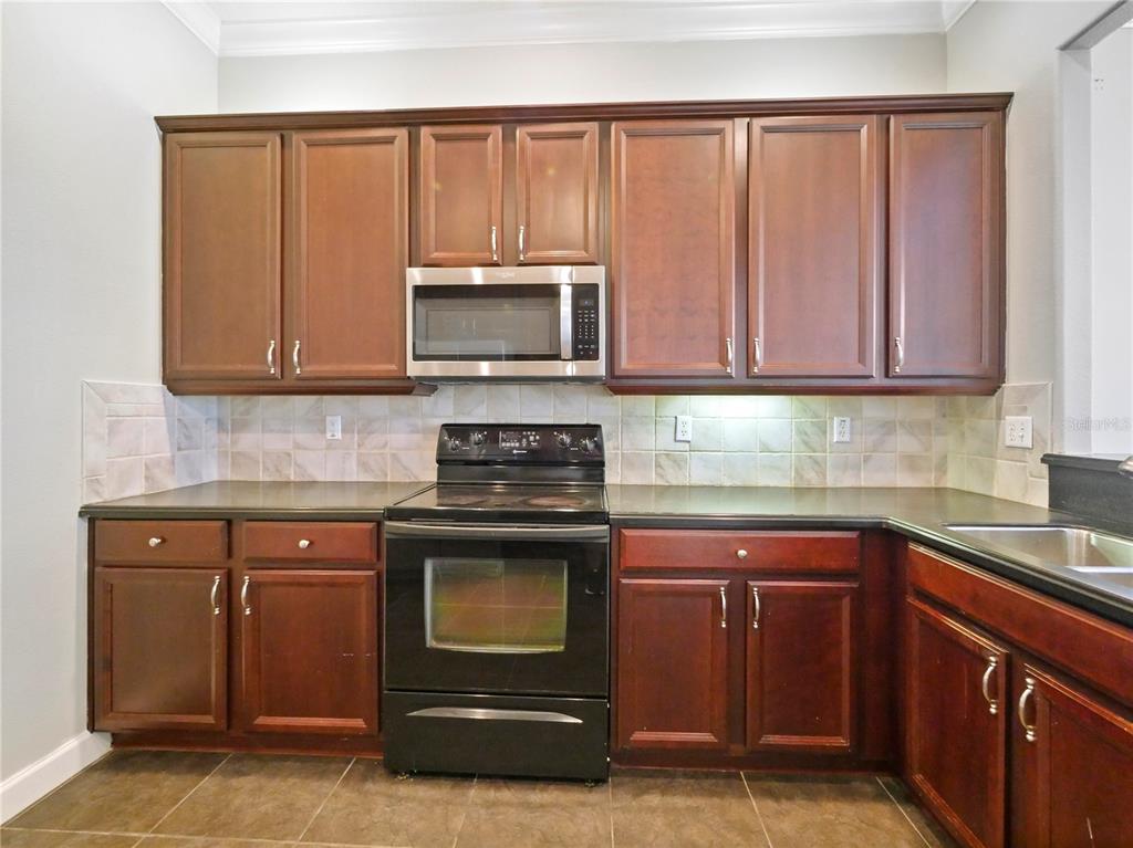 7710 Linkside Loop Reunion, FL 34747 - Photo 27 of 33 a kitchen with granite countertop a stove top oven microwave and cabinets