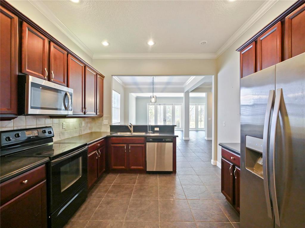7710 Linkside Loop Reunion, FL 34747 - Photo 5 of 33 a large kitchen with stainless steel appliances granite countertop a stove and a refrigerator