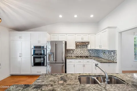 a kitchen with stainless steel appliances kitchen island granite countertop a refrigerator and a sink