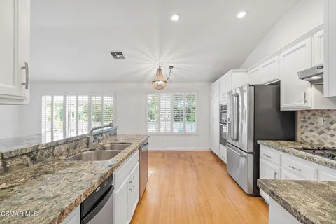 a kitchen with granite countertop a sink stove and refrigerator