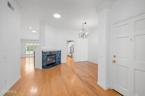 an empty room with fireplace wooden floor and chandelier