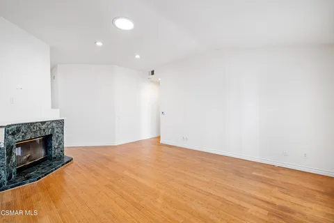 a view of empty room with wooden floor and fireplace