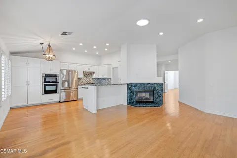 a view of kitchen with kitchen island granite countertop a stove top oven a sink and a counter top space
