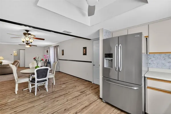 a kitchen with stainless steel appliances granite countertop a refrigerator stove a dining table and chairs with wooden floor