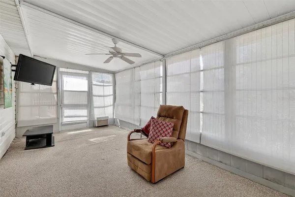 a living room with furniture a flat screen tv and a floor to ceiling window