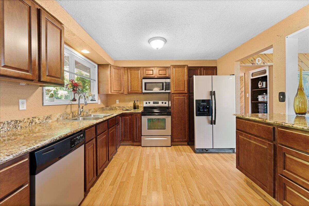4093 Old Upton Road Central Point, OR 97502 - Photo 5 of 23 a kitchen with stainless steel appliances granite countertop a refrigerator a sink dishwasher a stove with wooden cabinets and floor