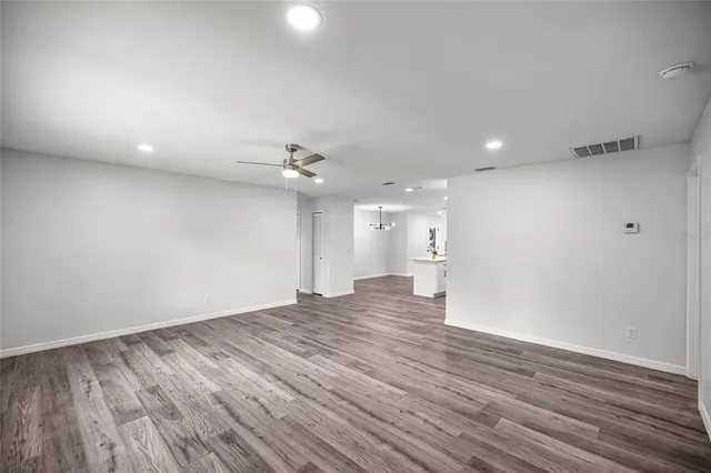 a view of an empty room with wooden floor and a ceiling fan