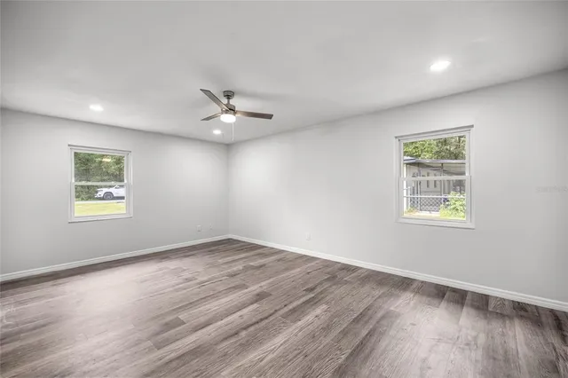 a view of an empty room with a window and wooden floor
