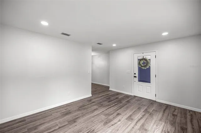 an empty room with wooden floor and natural light