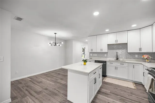a kitchen that has a lot of white cabinets and wooden floor