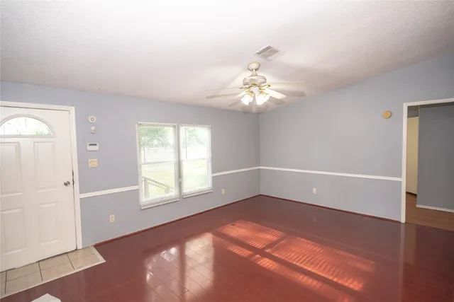 an empty room with windows and chandelier fan