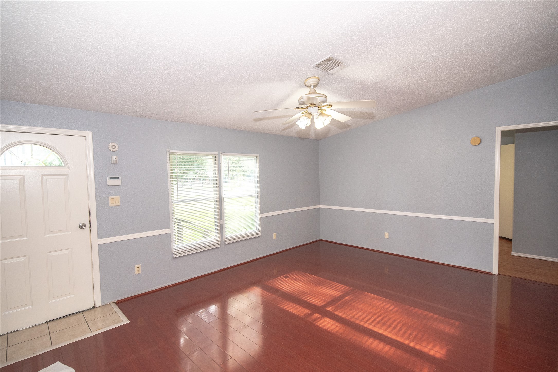 11804 Trickey Road Houston, TX 77067 - Photo 3 of 9 an empty room with windows and chandelier fan