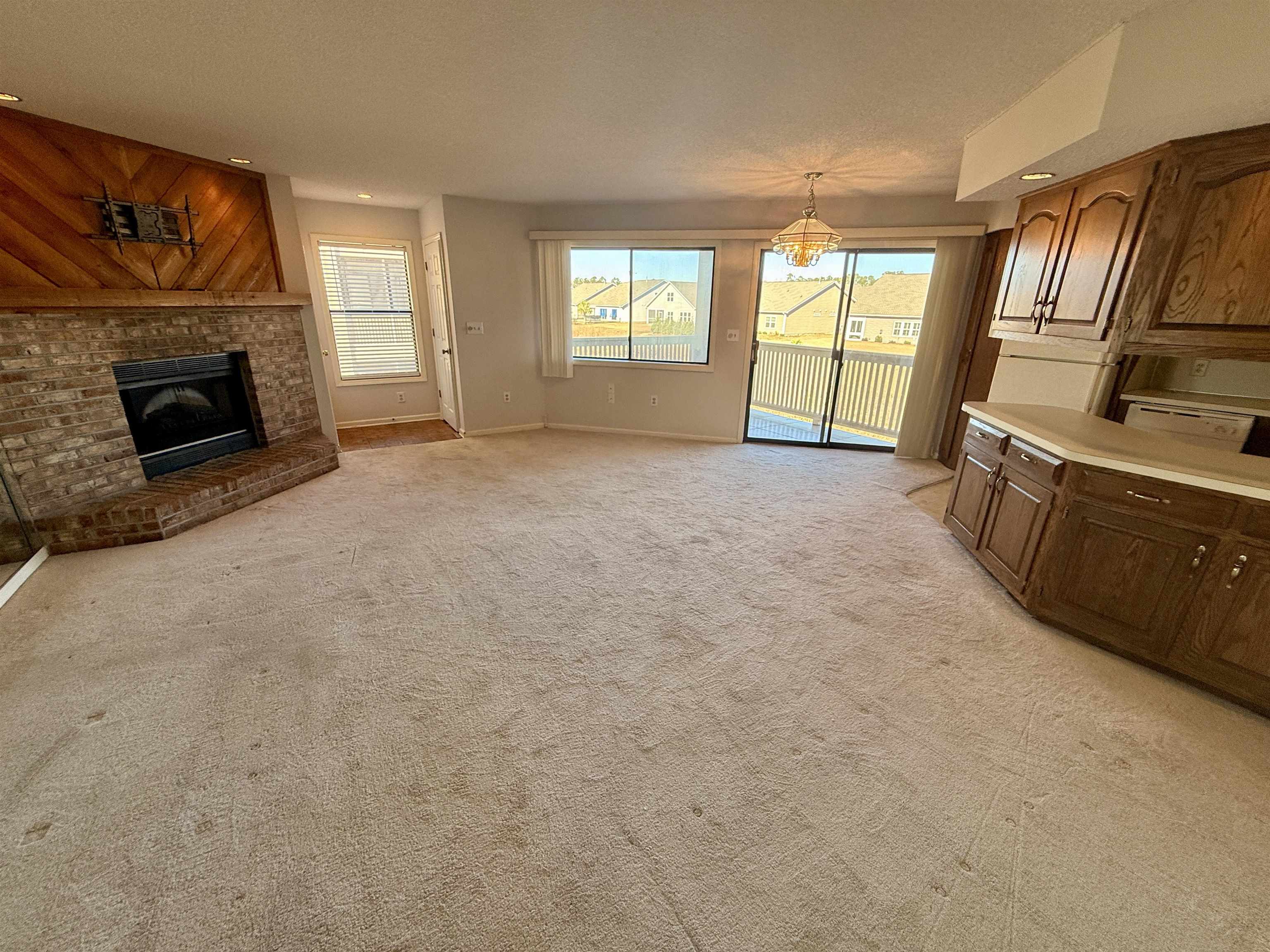 4230 Pinehurst Circle, Unit K4 Little River, SC 29566 - Photo 2 of 25 Unfurnished living room featuring healthy amount of natural light, a fireplace, recessed lighting, light carpet, and a chandelier