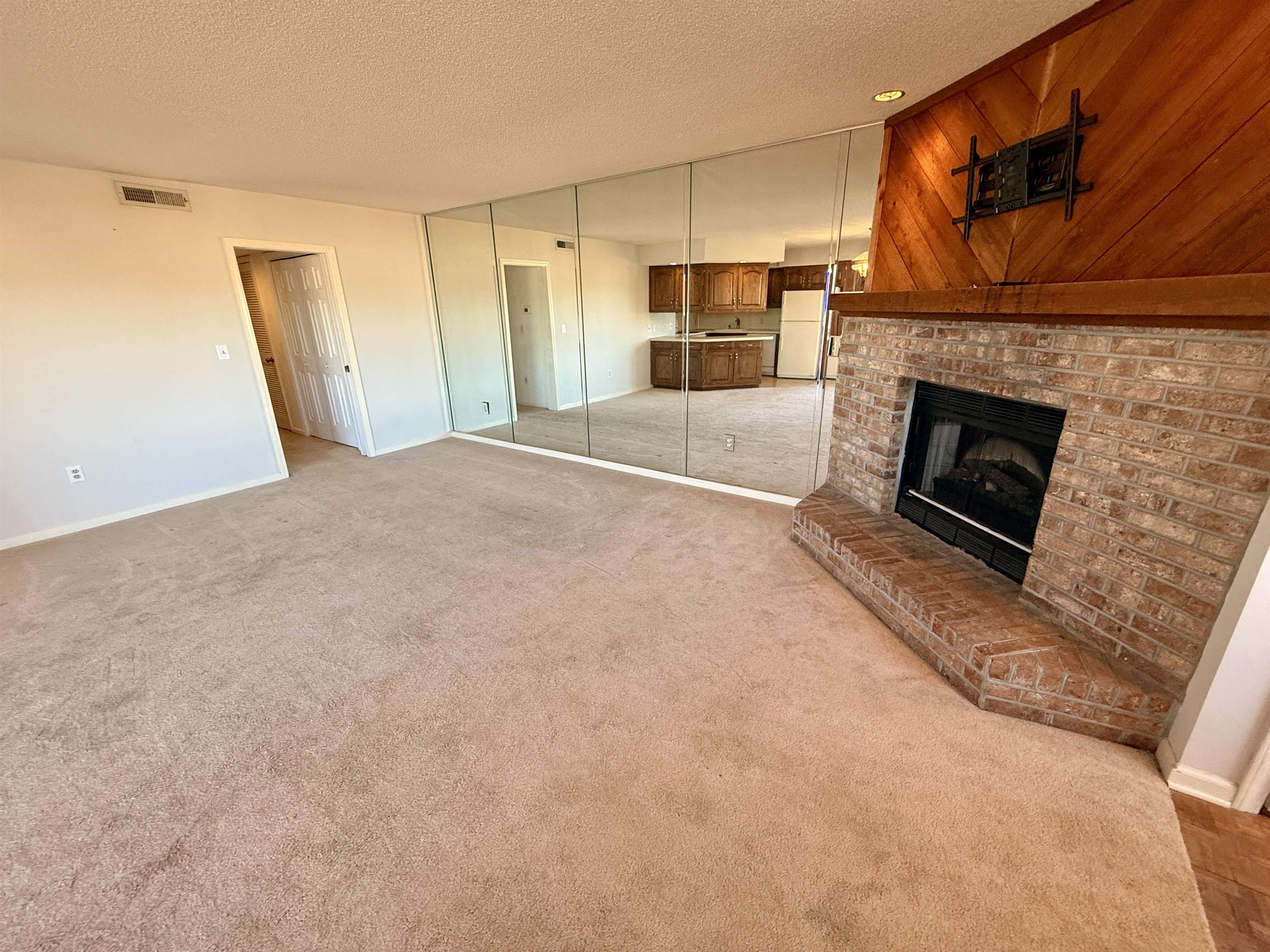 4230 Pinehurst Circle, Unit K4 Little River, SC 29566 - Photo 3 of 25 Unfurnished living room with light carpet, a brick fireplace, and a textured ceiling