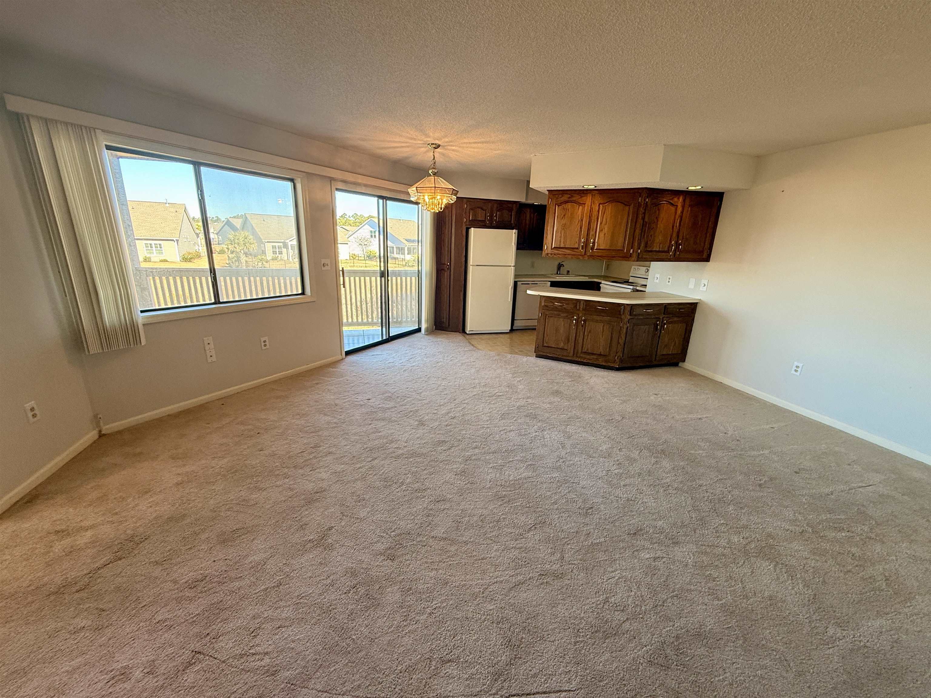 4230 Pinehurst Circle, Unit K4 Little River, SC 29566 - Photo 25 of 25 Kitchen with a chandelier, white appliances, light countertops, a textured ceiling, and open floor plan