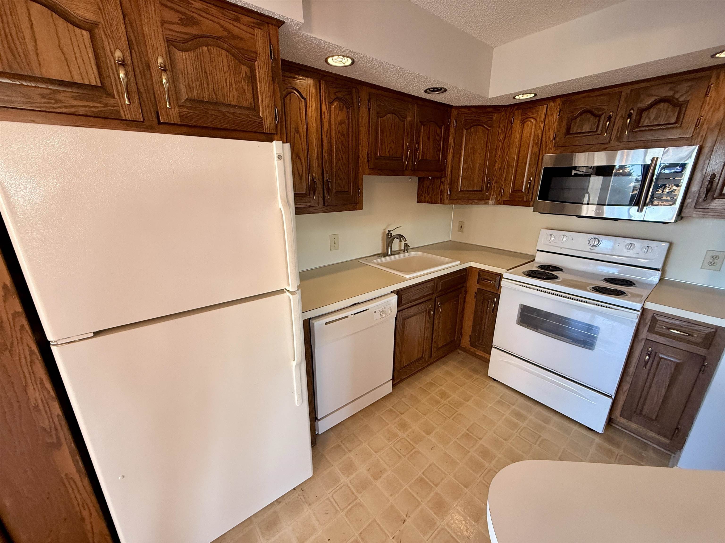 4230 Pinehurst Circle, Unit K4 Little River, SC 29566 - Photo 6 of 25 Kitchen with white appliances, light countertops, a textured ceiling, recessed lighting, and dark brown cabinetry