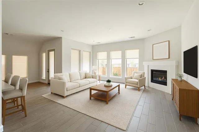 a living room with stainless steel appliances kitchen island wooden floors and white walls