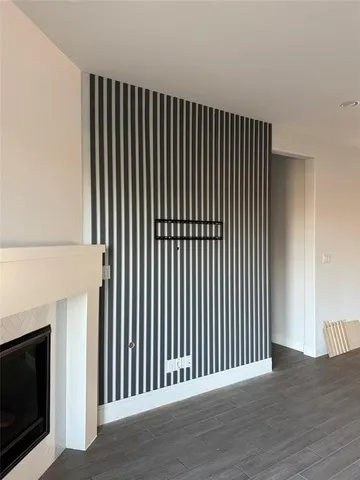 a living room with stainless steel appliances kitchen island wooden floors and white walls