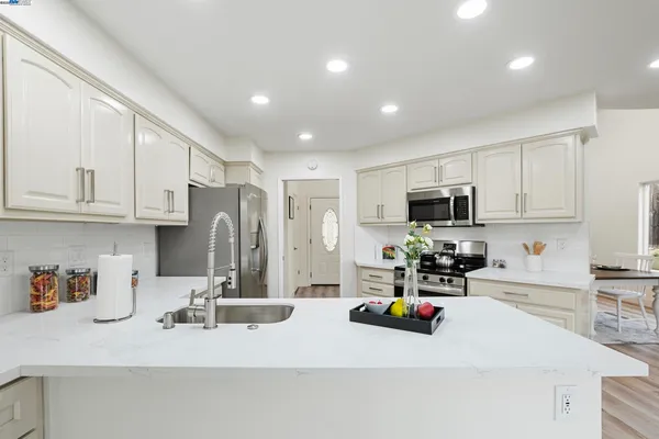 a living room with stainless steel appliances kitchen island granite countertop furniture a sink a rug and a kitchen view
