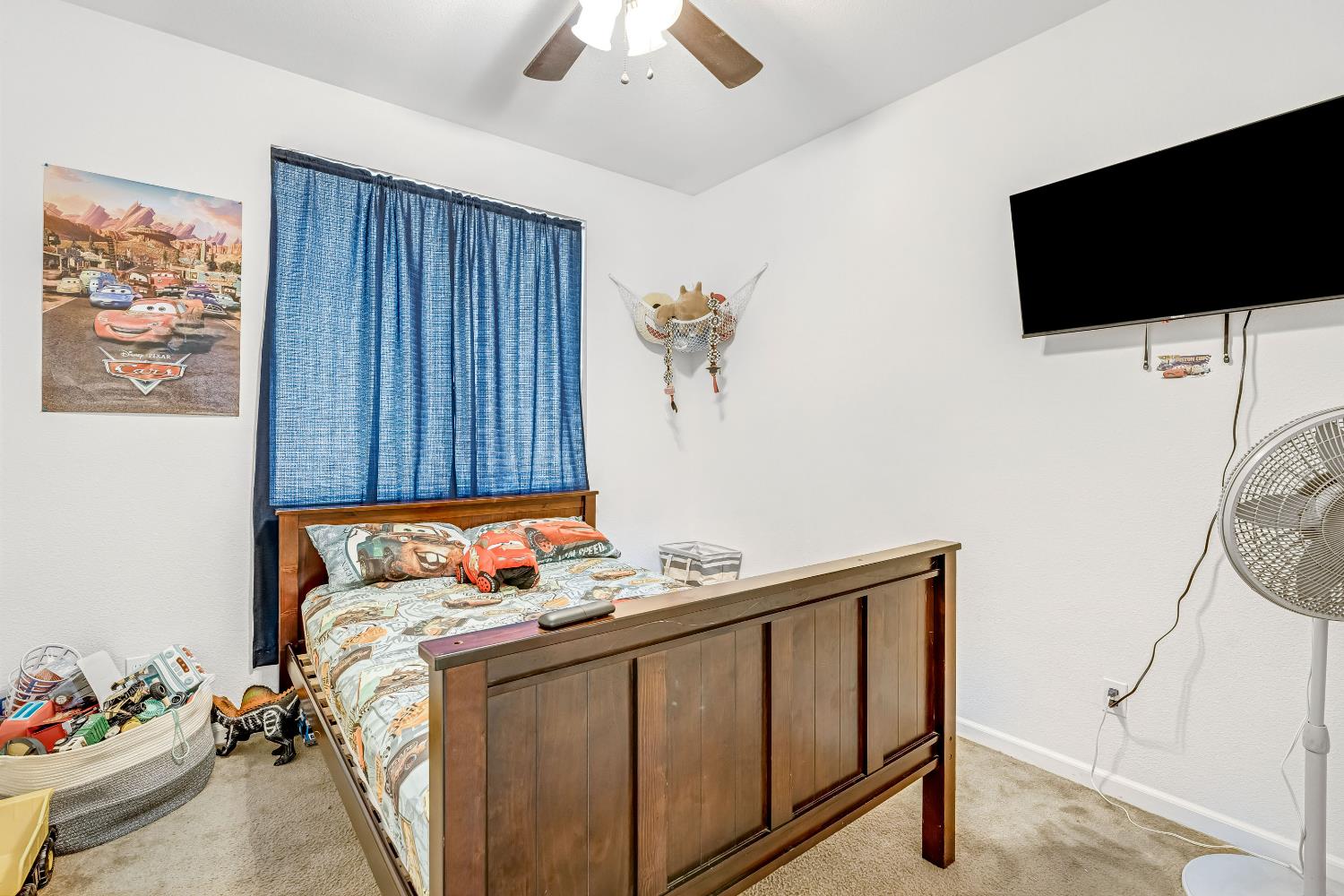 1981 Dunbar Way Dinuba, CA 93618 - Photo 8 of 12 a bedroom with a bed a flat screen tv and a chandelier