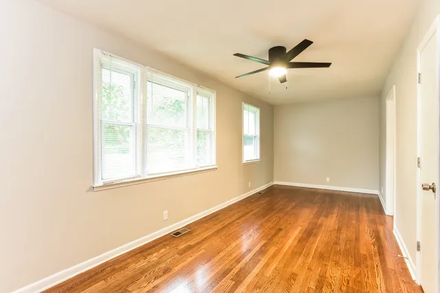 a view of empty room with wooden floor and fan