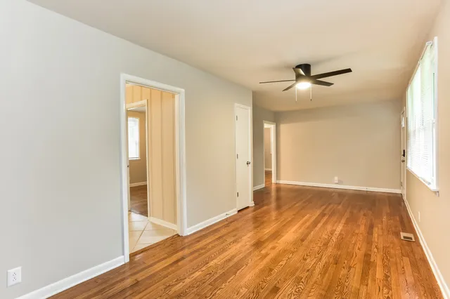 a view of empty room with wooden floor and fan