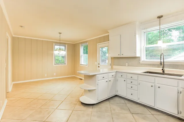 a kitchen with granite countertop white cabinets white appliances a sink and a window